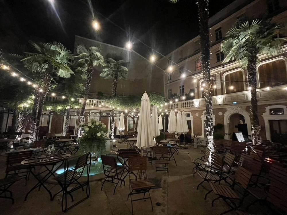 Cour intérieure à palmiers, guirlandes lumineuses et éclairage d’ambiance